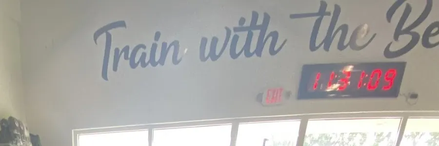 Red LED round clock on the wall under the words Train with the Best